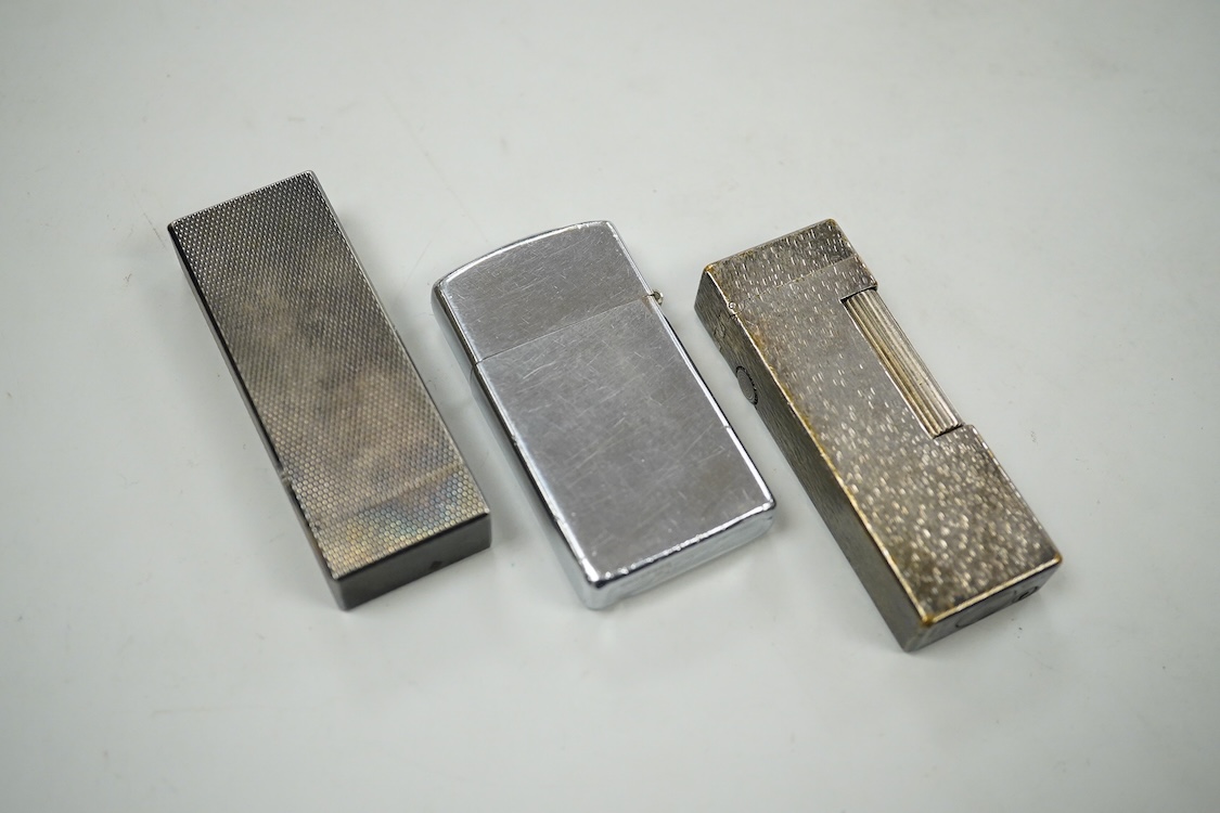 Two Dunhill rollagas silver plated lighters, barley pattern and rusticated 6.5cm long and a U.S.S. Coronado LPD-11, zippo lighter (3)